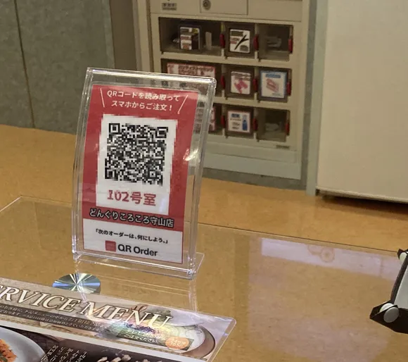 客室のテーブルに置かれた、スマホからご注文いただくためのQRコードの立て札